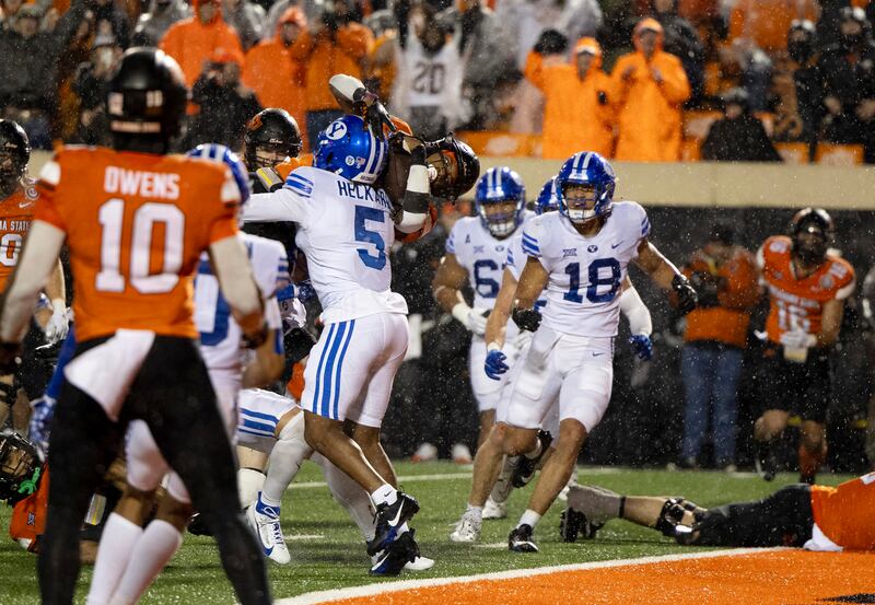 Oklahoma State running back Ollie Gordon II (0) dives over BYU cornerback Eddie Heckard (5) for a touchdown during the second overtime in an NCAA college football game Saturday, Nov. 25, 2023, in Stillwater, Okla.