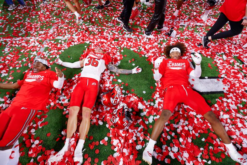 Utah Utes make snow angels in the confetti after beating the USC Trojans in the Pac-12 championship on Friday, Dec. 2, 2022.