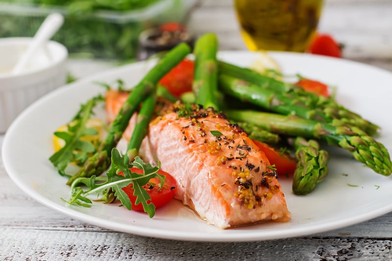 Baked salmon garnished with asparagus and tomatoes with herbs.