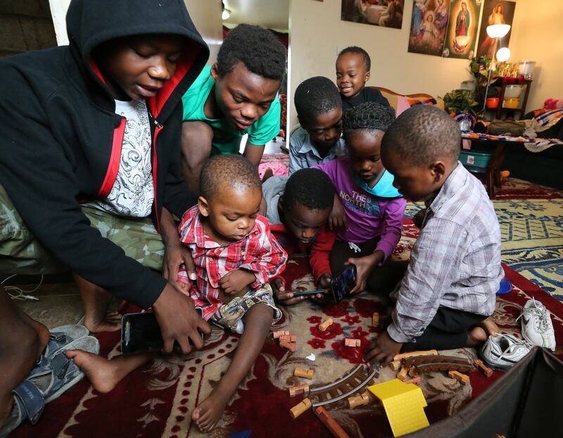 Children of Congolese refugees George and Amisa Ngunza play on cellphones in their apartment in Salt Lake City on Nov. 5, 2017.