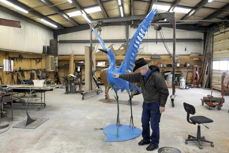 In this March 21, 2012, photo, Don Grazier stands near his steel sculpture of a great blue heron at his shop near Ronan, Mont. The 90-year-old cattleman-turned-artist makes life-size metal sculptures of bulls and wildlife, and larger-than-life birds and b