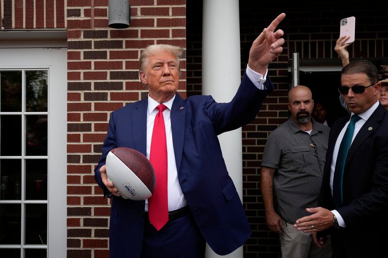 Former President Donald Trump holds a football before throwing it to the crowd before a college football game between Iowa State and Iowa on Sept. 9, 2023, in Ames, Iowa.