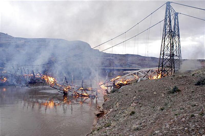 The 92-year-old Dewey Bridge spanning the Colorado burns Sunday near Moab. It caught fire when a boy playing with matches along the riverbank caused a brush fire. Winds spread the fire over 10 acres.