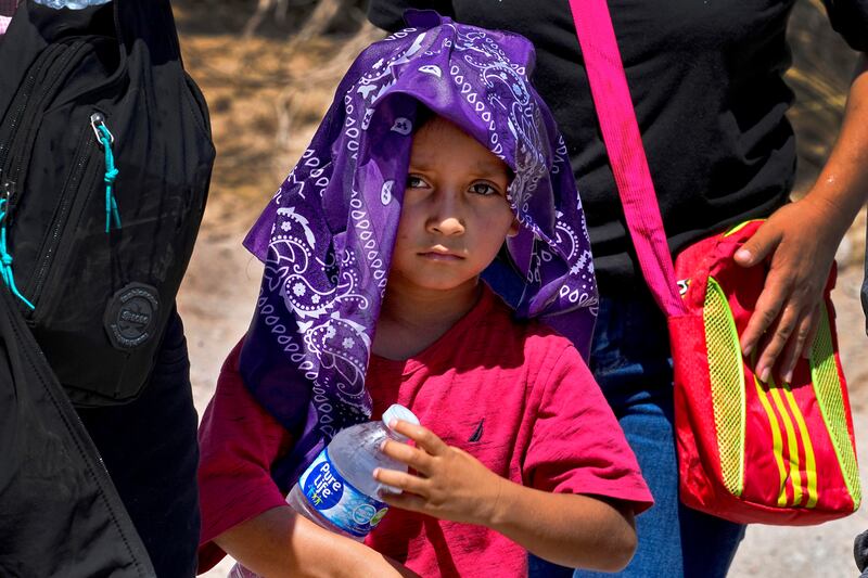 A young child and his mother cool down with a wet bandana and a bottle of water near Lukeville, Arizona.