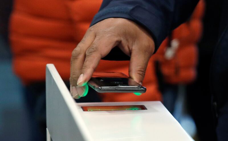 FILE- In this Jan. 22, 2018, file photo a shopper scans an Amazon Go app on a cellphone while entering an Amazon Go store in Seattle. A small number of restaurants and stores are going cash-free in the U.S., looking to cater to customers who increasingly