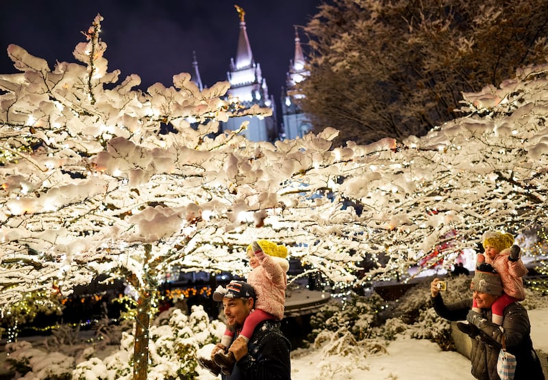 Jake McElheny carries his daughter, Ella, 2, while his wife, Christi, carries Ella’s twin sister, Grace, as they check out the Christmas lights display at Temple Square in Salt Lake City.