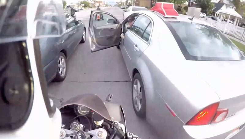 In this still frame of a video taken by motorcyclist Collin Hansen, a driver opens his door as Hansen lane filters on University Avenue in Provo on Sunday, June 16, 2019. Utah’s lane filtering law for motorcyclists has been on the books for a month, but t