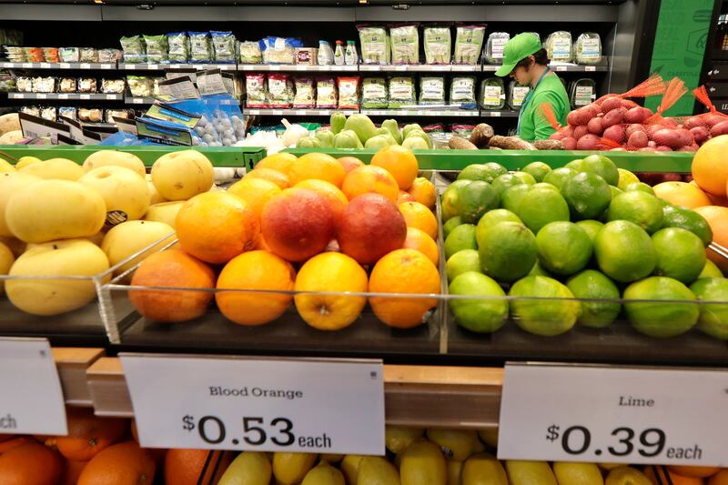 A worker checks items on a shelf in the produce section of an Amazon Go Grocery store set to open soon in Seattle’s Capitol Hill neighborhood.