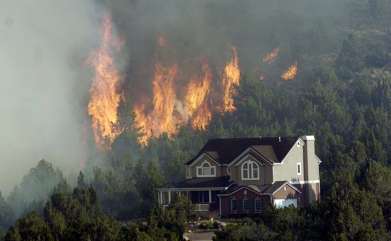 Flames burn very close to homes in the New Harmony Heights area of southern Utah near St. George June 27, 2005.