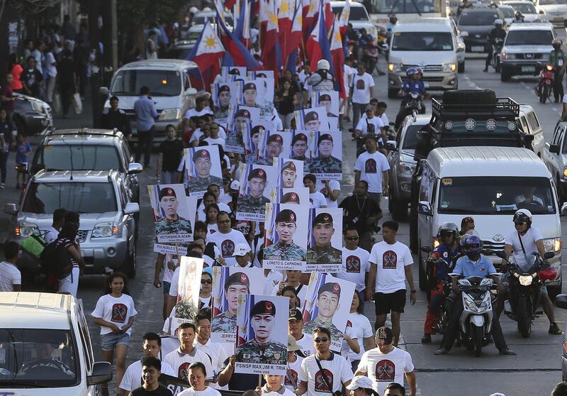 In this Sunday March 8, 2015, file photo, family and supporters march as they hold some of the pictures of the 44 police commandos killed during a recent operation against Southeast Asia's top terrorist suspect Malaysian Zulkifli bin Hir, also known as Ma