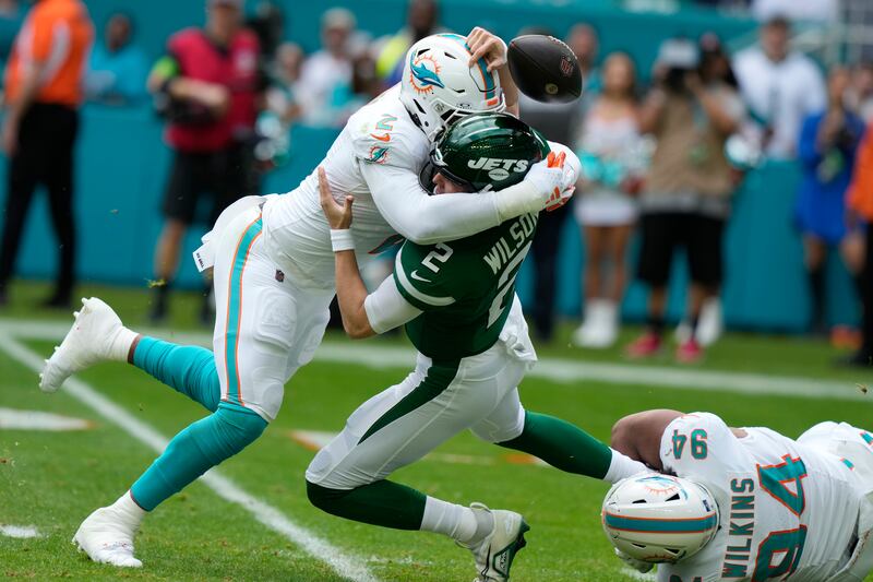 New York Jets quarterback Zach Wilson (2) fumbles the ball as he is sacked by Miami Dolphins defensive tackle Christian Wilkins (94) and linebacker Bradley Chubb (2) during the first half of an NFL football game, Sunday, Dec. 17, 2023, in Miami Gardens, Fla. (AP Photo/Lynne Sladky)