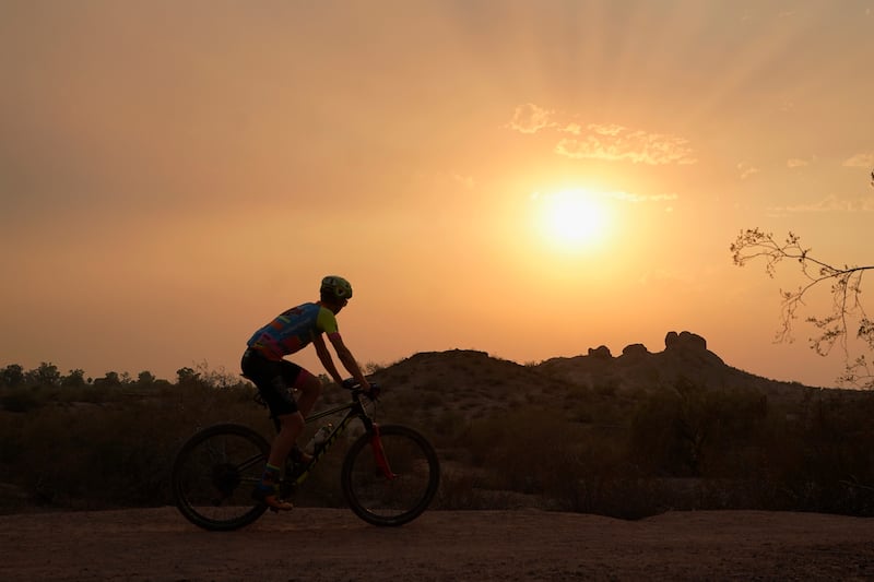 A cyclist bikes where temperatures hit 115 degrees Tuesday.