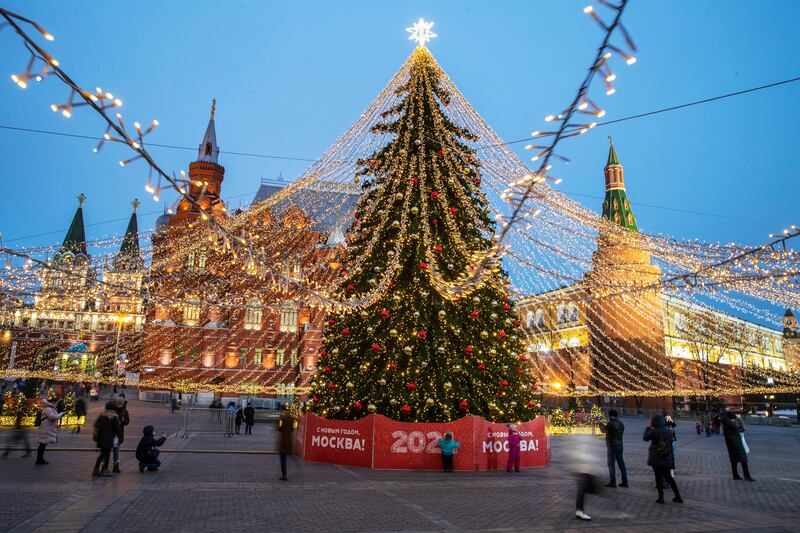 People walk past a Christmas tree.