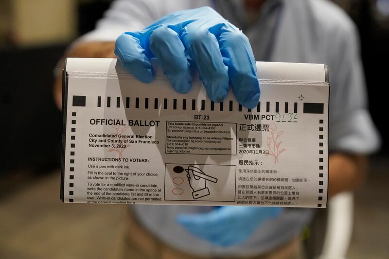 San Francisco Department of Elections ballot processors William Logan holds a ballot at a voting center in San Francisco, Sunday, Nov. 1, 2020.