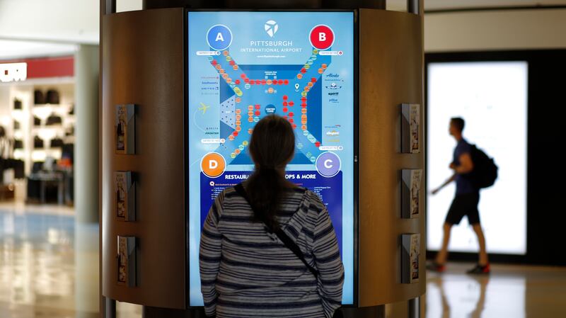 This June 9, 2019 photo shows a woman looking at a map of the Airside Terminal at Pittsburgh International Airport in Imperial, Pa.