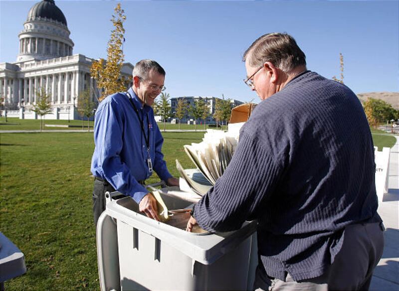Colin Schrock of Columbus Secure Shredding, left, assists K. Ray Hammond as he dumps documents into a can for shredding. In recognition of National Identity Theft Awareness Week, the Commerce Department and Zions Bank are hosting a weeklong event to allow