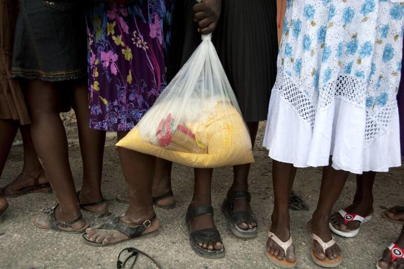 In this May 26, 2013 photo, a woman holds a bag of food in line as the government distributes food in Petion-Ville, Haiti.