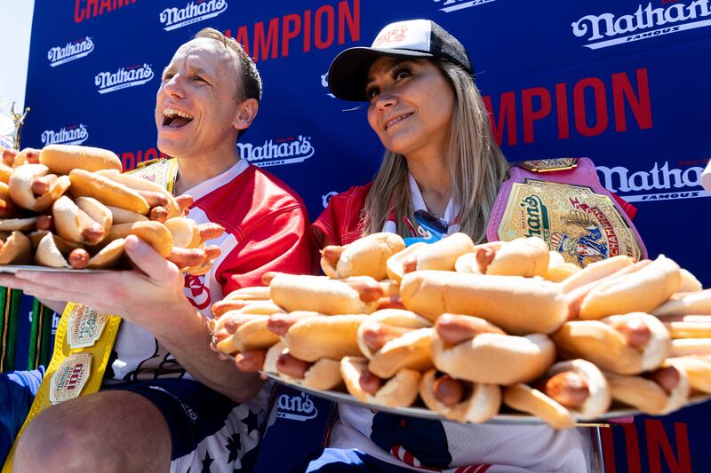 Joey Chestnut and Miki Sudo pose with hot dogs after winning a Fourth of July hot dog eating contest.