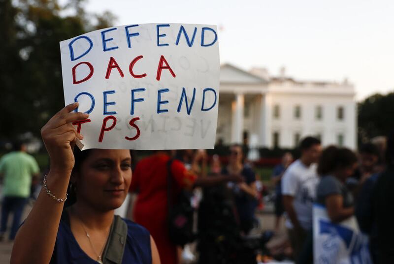 A woman holds up a sign that reads "Defend DACA Defend TPS" during a rally supporting Deferred Action for Childhood Arrivals, or DACA, outside the White House in Washington, Monday, Sept. 4, 2017. TPS stands for "Temporary Protected Status."
