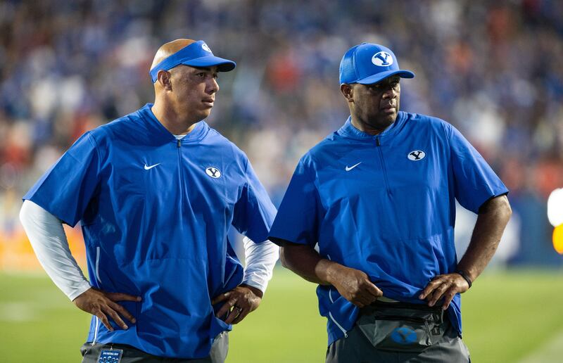 BYU recruiting coordinator Jasen Ah You, left, and on-campus specialist Jack Damuni talk during a game in Provo.
