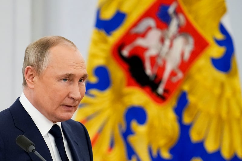 Russian President Vladimir Putin stands in front of the Russian standard flag.
