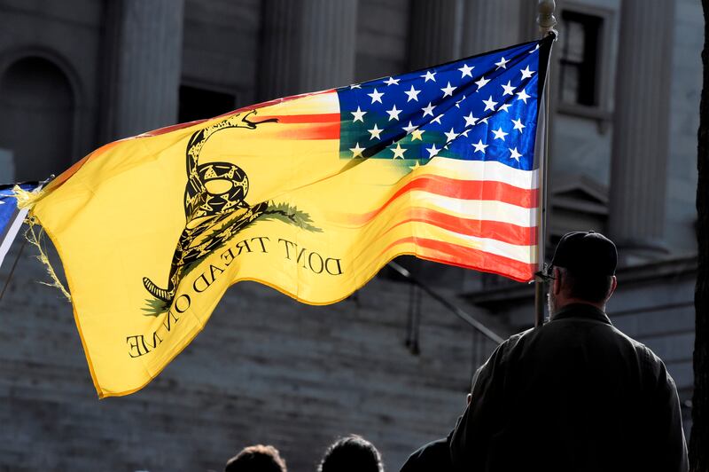 A man holds a “Don’t Tread On Me” flag and listens to a speaker during a rally at South Carolina’s Statehouse.