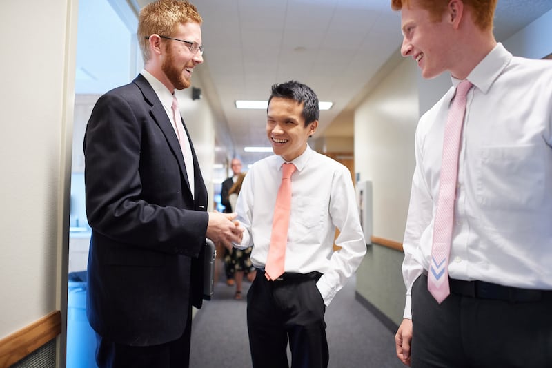 A young man who is blind shakes hands with another young man at church.