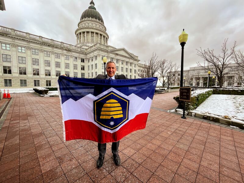 Sen. Dan McCay, R-Riverton, poses with a physical version of the proposed new Utah state flag design at the Utah Capitol on Wednesday. His bill pushing for the flag passed the Senate Business and Labor Committee.