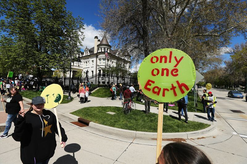 People hold up signs while marching to the Governor’s Mansion during the Utah People’s Climate March in Salt Lake City in 2017.
