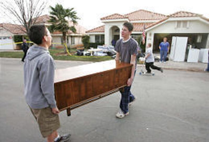 Volunteers Cody Monson and Adam Petersen move a wooden chest across the street after the flood.