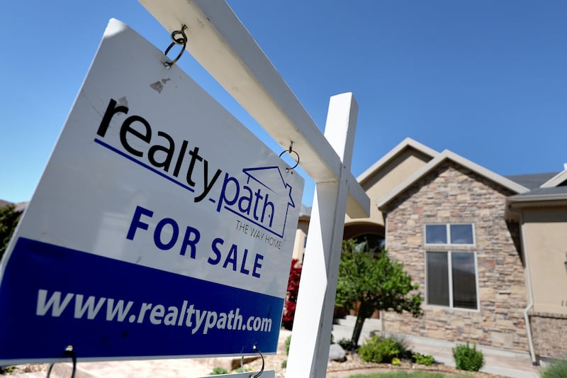 A “For Sale” sign is posted in the yard of a house in Sandy, Utah.