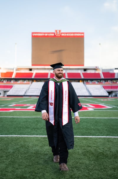 Former Utah center Jaren Kump and recent Utah graduate walks in cap and gown in an empty Rice-Eccles Stadium in Salt Lake City.