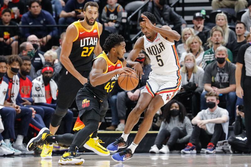 Utah Jazz guard Donovan Mitchell dribbles the ball past New Orleans’ Herbert Jones as Jazz center Rudy Gobert looks on.