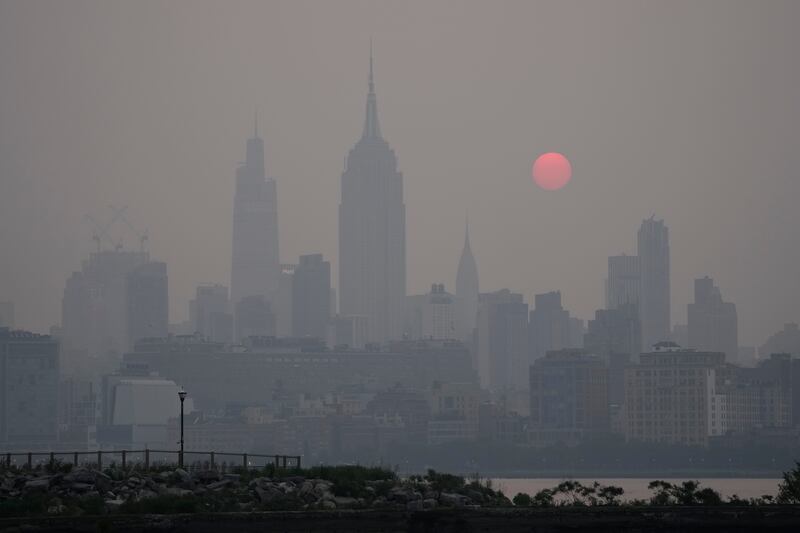 The sun rises over a hazy New York City skyline as seen from Jersey City, N.J.