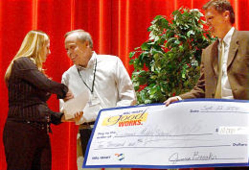 Debbie Erickson, personnel manager of the Midvale Wal-Mart, congratulates Eastmont reading teacher Jon Van Wagoner on Wednesday.