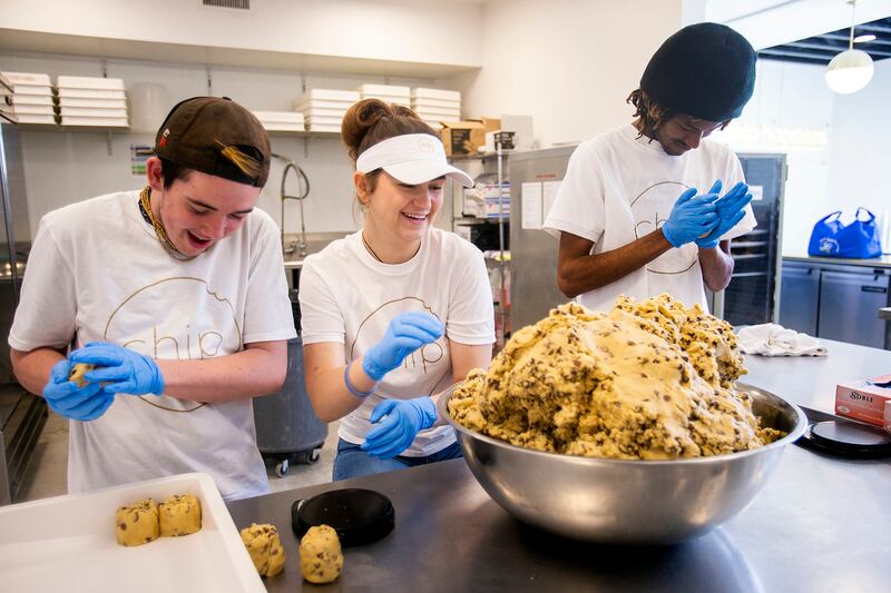Logan McDougal, Elizabeth Knudsen and Cam Grene make the individual cookie balls and place them in trays as they work at Chip Cookies in Salt Lake City on Monday, March 25, 2019.