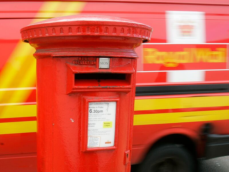 A Royal Mail postal delivery van drives past a mail collection box in London.
