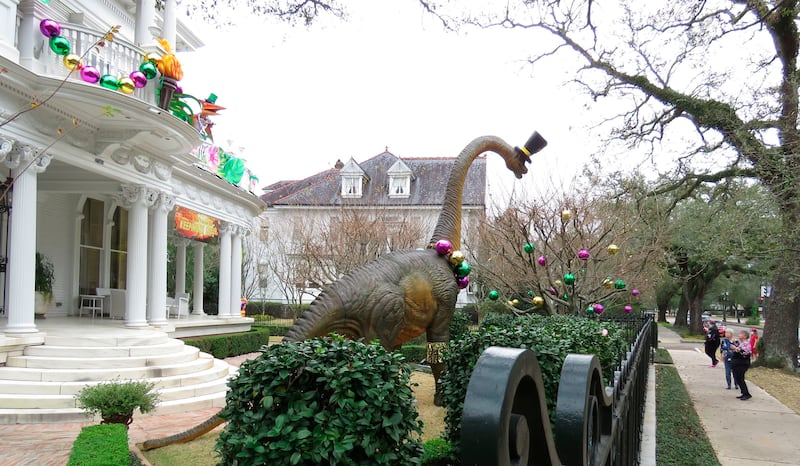 Passersby look at dinosaurs on the balcony of a mansion on St. Charles Avenue in New Orleans, Tuesday, Jan. 26, 2021. The banner says “Thank you, Mayor, for keeping us safe.”