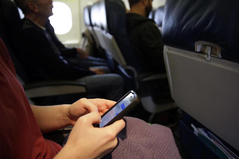 This Oct. 31, 2013 file photo shows a plane passenger checking her cell phone before a flight in Boston.