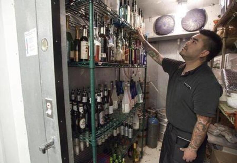 In this June 1, 2011 photo, Chris Taketa looks for liquor stored in a walk-in freezer in the back of the Dojo sushi restaurant in Salt Lake City. The so-called "Zion wall" that shields diners from alcohol displays and drink mixing in Utah restaurants won