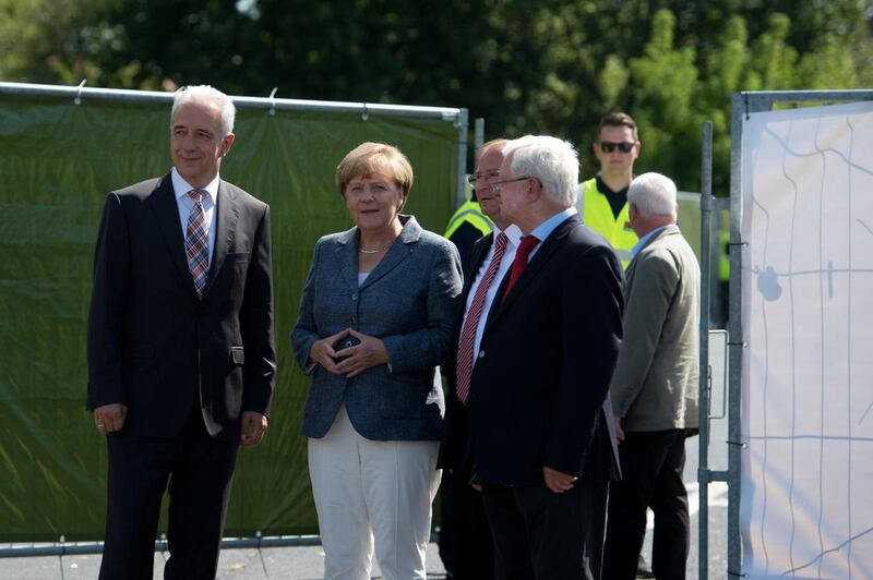 German Chancellor Angela Merkel, second left, arrives at the refugee shelter in Heidenau and is welcomed by the German Red Cross president Rudolf Seiters, right, the prime minister of Saxony Stanislaw Tillich , left, and Heidenau's mayor Juergen Opitz .