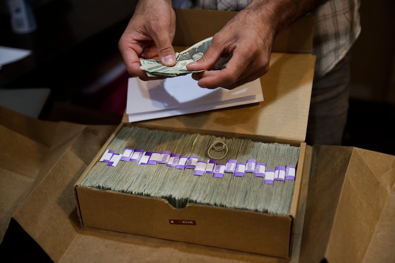 In this June 27, 2017, file photo, Jerred Kiloh, owner of the Higher Path medical marijuana dispensary, prepares his monthly tax payment, $40,131.88 in cash, in Los Angeles. For Kiloh, the cash is a daily hassle. It needs to be counted repeatedly to safeg