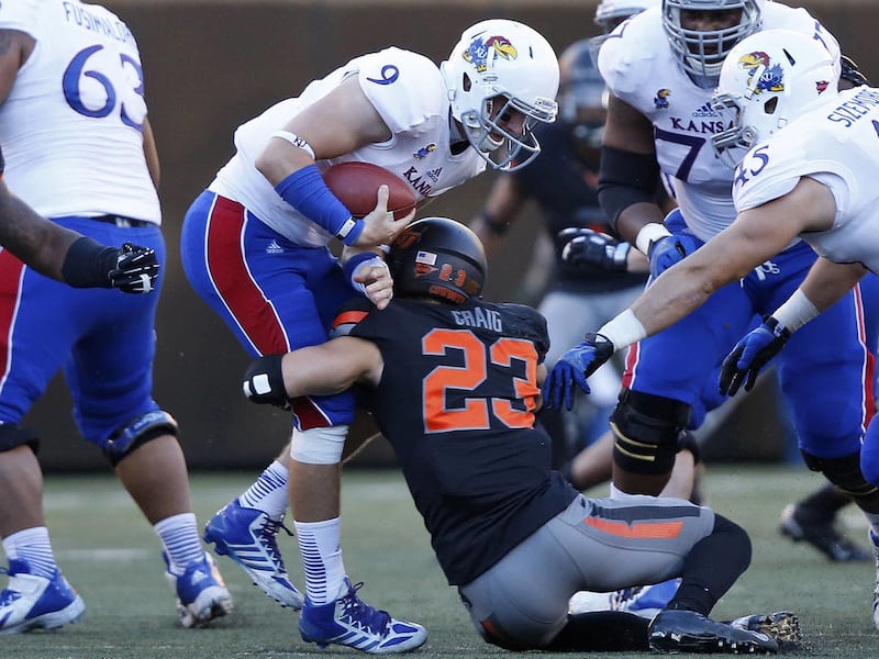 Kansas quarterback Jake Heaps (9) is sacked by Oklahoma State defender Zack Craig (23) in the second quarter of an NCAA college football game in Stillwater, Okla., Saturday, Nov. 9, 2013.