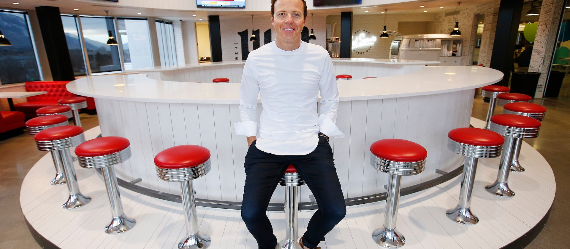 Ryan Smith, Qualtrics CEO, sits on a barstool at the headquarters’ Hub in Orem, Utah. Ryan Smith’s net worth is around $1.3 billion.