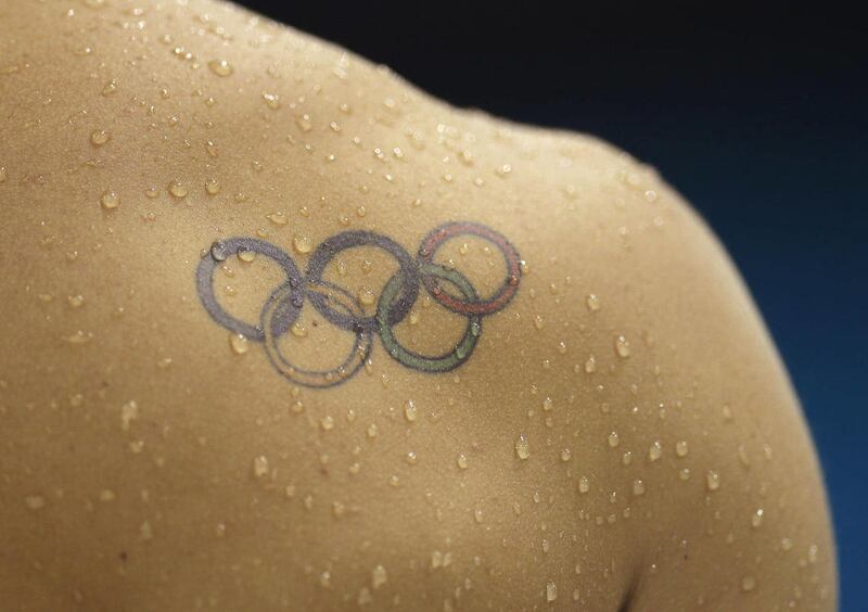 In this Thursday, July 26, 2012 photo, water droplets fall across a tattoo of the Olympic rings on the shoulder of diver Illya Kvasha of Ukraine, during a diving practice session at the Aquatics Center at the Olympic Park ahead of the 2012 Summer Olympics
