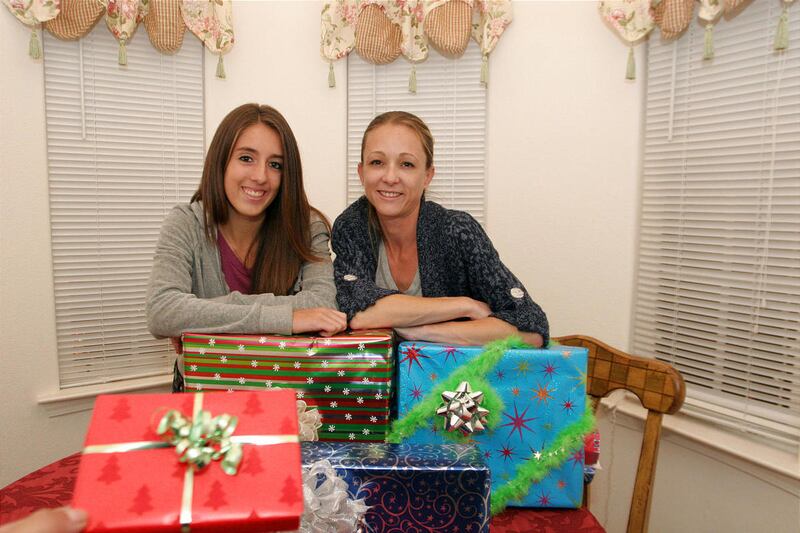 Chelsea Fiero, 16, left, and her mother, Julie Allen, show off some of their wrapped holiday gifts at home in Leandro, California, on December 2, 2010. More stores are no longer offering gift-wrapping services so buyers must do it themselves.