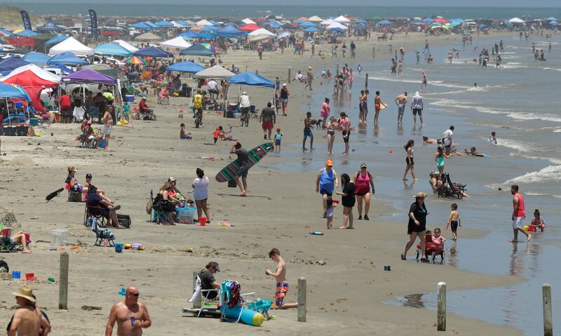 In this May 23, 2020 file photo, people gather on the beach in Port Aransas, Texas. Beachgoers are being urged to practice social distancing to guard against COVID-19.