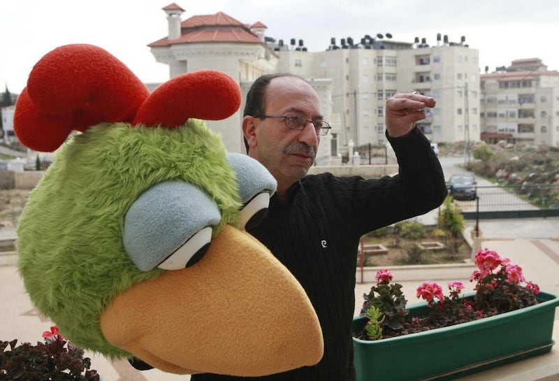 In this photo taken Thursday, Jan. 5, 2012, actor Rajai Sandouka, holds Kareem, the main character of Sharaa Simsim, the Palestinian version of Sesame Street, at the program's offices in West Bank city of Ramallah. The producers of the iconic children's p