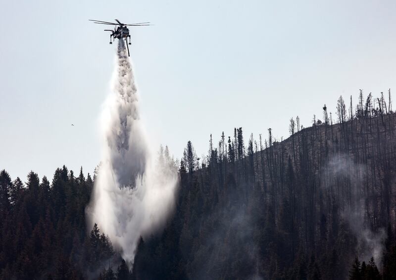 A helicopter drops water on hot spots as crews fight the Parleys Canyon Fire near Park City.