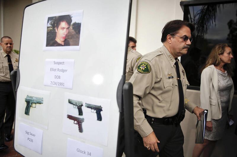 Santa Barbara County Sheriff Bill Brown, right, walks past a board showing the photos of suspected gunman Elliot Rodger and the weapons he used in Friday night's mass shooting that took place in Isla Vista, Calif., after a news conference on Saturday, May